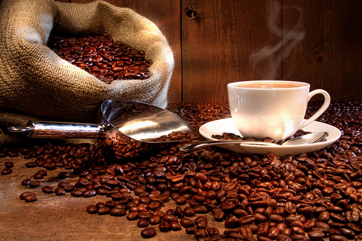 Carta da parati chicchi di caffè sotto una tazza di caffè aromatico