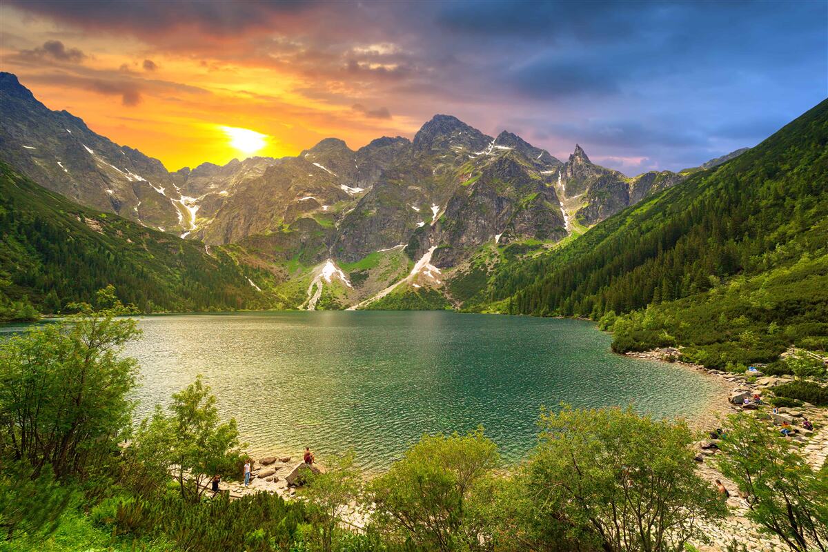 Carta da parati spettacolare tramonto dietro le catene montuose vicino al lago